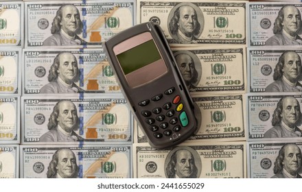 Terminal for cashless payments. Concept - refusal of cash transactions. Hundred dollar bills near cash register terminal. Concept - sale equipment for working with bank cards. Payment upon purchase - Powered by Shutterstock