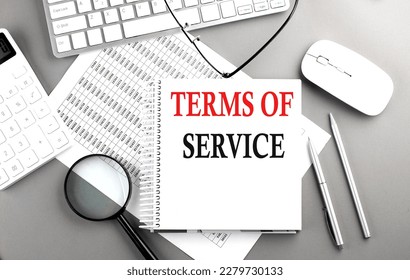 TERMS OF SERVICE text on a notepad on chart with keyboard and calculator on grey background