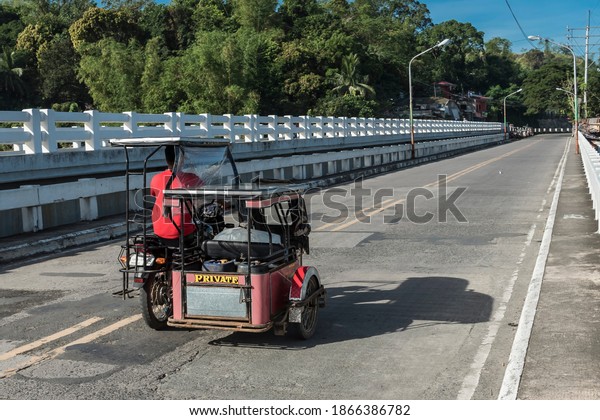 Ternate, Cavite - Dec 2020: A private tricycle\
crosses the Maragondon bridge, part of Governor\'s Drive, a highway\
traversing Ternate.