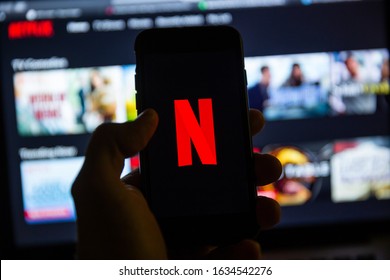 TERNOPIL, UKRAINE - JANUARY 11, 2020: Man holds iPhone 7 with red Netflix brand logo on its screen in the evening. Netflix is a global video streaming service.