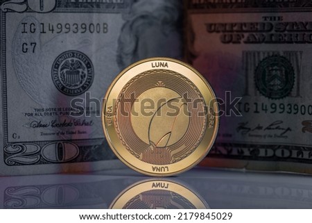 Terra Luna LUNC Cryptocurrency Physical Coin Placed on reflective surface with twenty dollar bill behind.