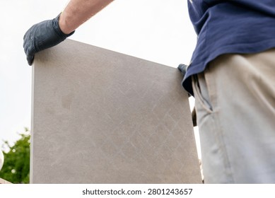  terrace paving process.Construction worker transporting a large tile slab for terrace flooring near residential building. professional tiling work. 