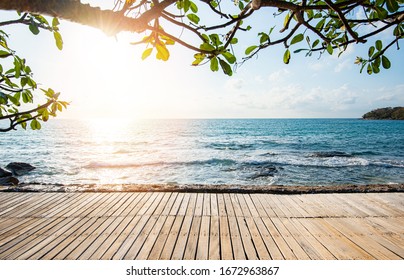 Terrasse Blick aufs Meer mit leerem Holztisch auf der Strandlandschaft Natur mit Sonnenuntergang oder Sonnenaufgang / Holzbrücke Balkon Blick auf das idyllische Meer Silhouette tropischer Baum Sommerurlaub Strand 