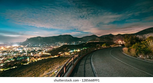 Terracina, Italy. Top View Skyline Cityscape City In Evening Night Illuminations. Night Open Road And Beautiful Cityscape. Panorama, Panoramic View.