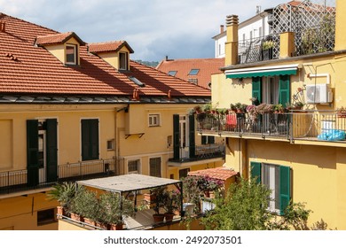 Terracotta rooftops and charming balconies with potted plants adorn this picturesque Mediterranean residential scene. Sunlit yellow buildings with green shutters create a warm and inviting atmosphere - Powered by Shutterstock