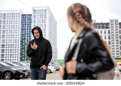 Terrible Man Is Calling Little Child Girl On City Street, Kidnapping. Criminal Guy In Black Wear Commit Crime, Ask Girl To Came To Him. Focus On Guy. Caucasian Child In Black Leather Jacket