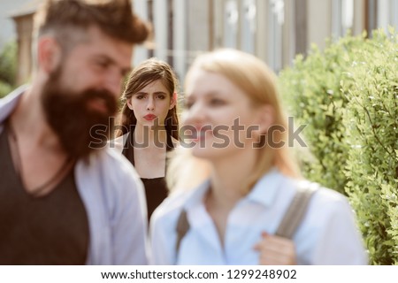 Terribly jealous of them. Romantic couple of man and woman dating. Bearded man cheating his girlfriend with another woman. Jealous woman look at couple in love on street. Unhappy girl feeling jealous.