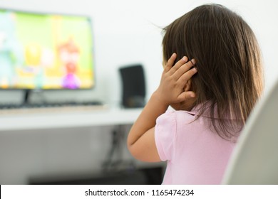 A terrified child, afraid of the loud sounds from the television. Autism.