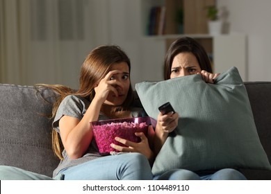 Terrified Friends Watching Tv In The Night Sitting On A Couch In The Living Room At Home