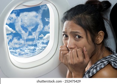 Terrified passenger on a plane. Woman watching skulls death of clouds on the sky from window of the flying aircraft.  Danger warning sign for airplane on heaven. - Shutterstock ID 252475429