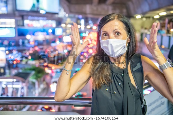 Terrified woman in the city traffic wearing\
breathing mask for pollution and\
coronavirus.