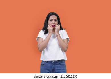 terrified woman giving fearful expression. Indian girl in fear looking away. Scared timid and insecure woman , screaming and looking terrified, shivering from fear, orange background