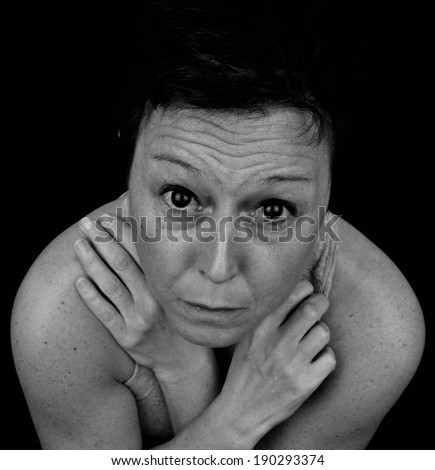 Terrified woman holding herself for protection. Black and white portrait.