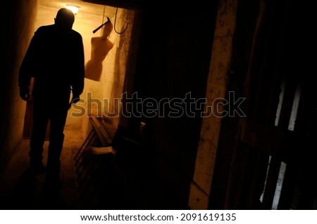 terrifying scene - a killer in a cellar with a hanging mannequin
