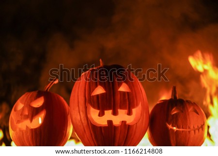 Terrifying symbols of Halloween - Jack-o-lanterns. Scary carved halloween pumpkins on black flaming fire background. All Hallows' Eve or All Saints' Eve.