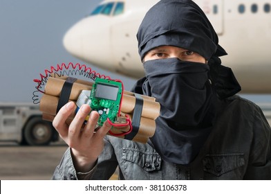 Terrorism Concept. Terrorist In Airport Holds Dynamite Bomb In Hand.