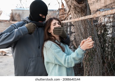 Terrorist aiming at female hostage outdoors