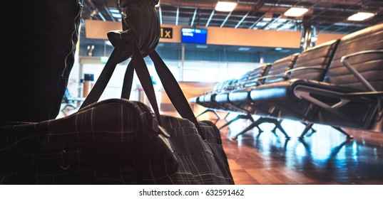 Terrorist in airport planning a bomb attack. Terrorism and security threat concept. Suspicious dangerous man in the shadows with black bag. Gate, bench and waiting area in the blurred background. 