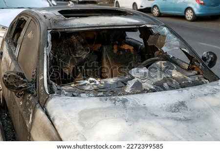 Terrorist attack. Windows shatter from the explosion. Setting fire to cars. Remains of a burned car. Burned out car on roadside down in the middle of the street. Burnt new car, vandalism, mafia.