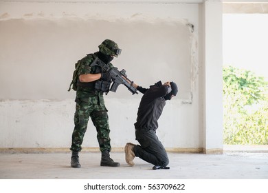 A Terrorist Being Arrested By A Soldier In A Building.