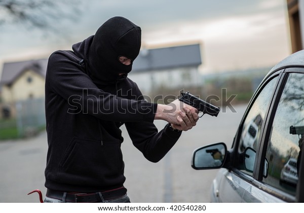 Terrorist or a car thief pointing a gun at the\
driver - car owner