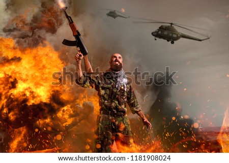 Terrorist with rifle stands in explosion and fire