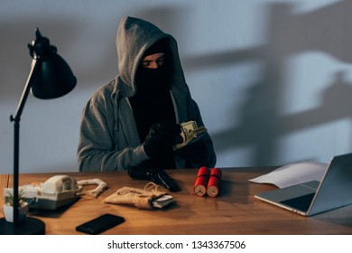 Terrorist Sitting In Room With Weapon And Counting Dollar Banknotes