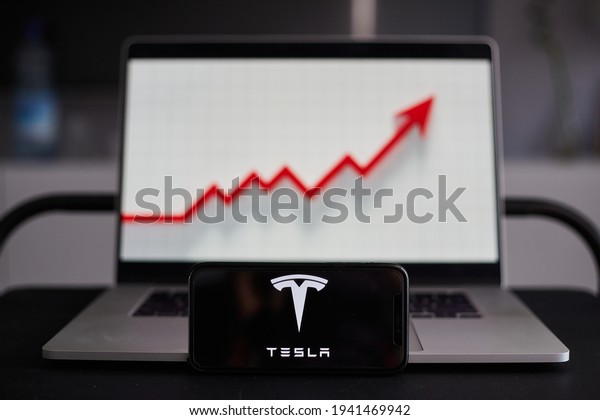 Tesla logo on a smartphone and the chart\
covering the last month with Tesla company stocks price. Graph.\
Medias, Romania\
23.03.2021