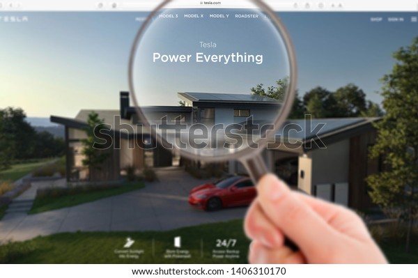 Tesla official\
website on the screen under a magnifying glass. Tesla is an\
American company that designs, manufactures, and sells electric\
cars. Moscow, Russia - May 20,\
2019