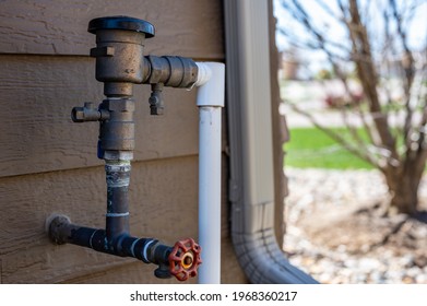 Test cocks, shut off valves, and vacuum breaker to a lawn sprinkler irrigation system on the outside of a residential house - Shutterstock ID 1968360217