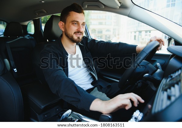 Test\
drive for auto. Pleasant overjoyed handsome man holding steering\
wheel and driving his car while expressing\
gladness