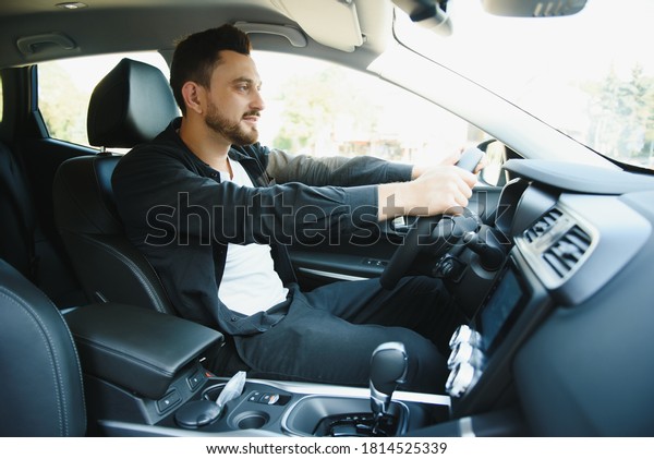 Test\
drive for auto. Pleasant overjoyed handsome boy holding steering\
wheel and driving his car while expressing\
gladness