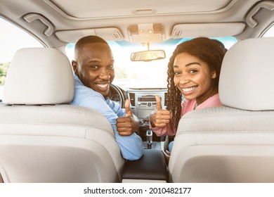 Test Drive, Great Ride, Good Car Concept. Portrait Of Excited African Amercan Couple Showing Thumbs Up Sign Gesture, Sitting On Front Seats In New Auto, Looking Vack At Camera Buying Vehicle In Store