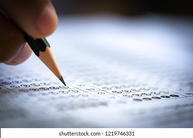 Test exam concept, pencil writing answer on paper answer of question in examination test. It assessment intended to measure knowledge, skill, aptitude, physical fitness, or classification students