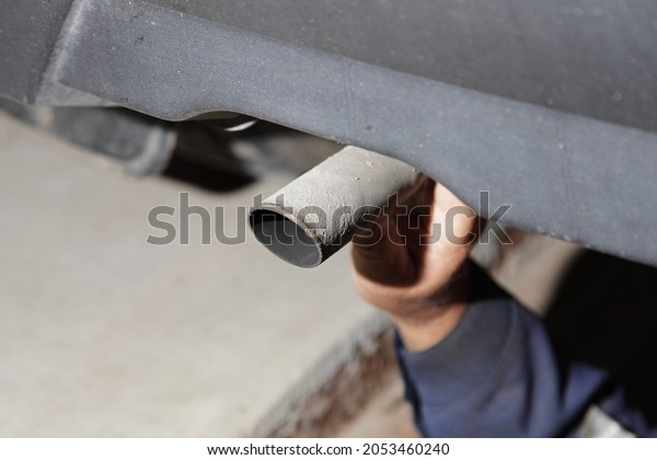 Test the exhaust system of the used car - a man\'s\
hand checks the exhaust silencer pipe clamp fastening under the\
bottom of the vehicle