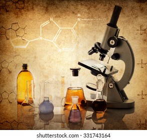 Test glass flask with solution and microscope in research laboratory. Science and medical background. Focus in the foreground.