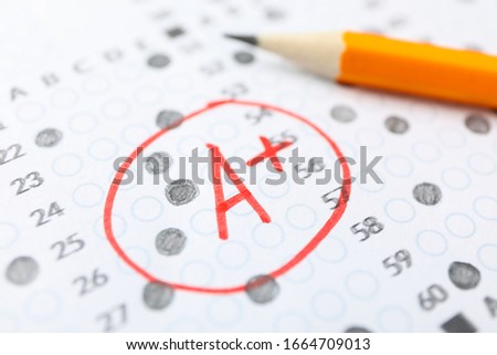 Test score sheet with answers, grade A+ and pencil, close up