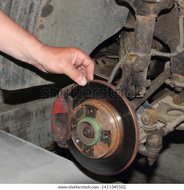 Test\
of thickness of the unvented brake disc, car brakes inspection -\
close up hand points your fingers at the brake\
disk