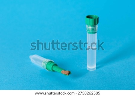 A test tube with a stool sample on a blue background, concept of stool research for pathogenic microflora and dysbacteriosis