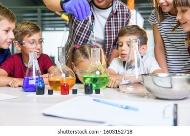 Test tubes with colorful liquid substances. Study of liquid states. Group school pupils with test tubes study chemical liquids. Science concept. Girls and boy providing experiment with liquids.