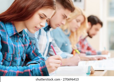 Testing. Closeup of young students sitting in a row and having test in their test-books - Powered by Shutterstock