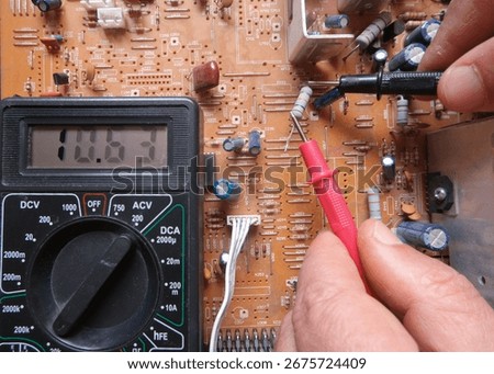 Testing an electronic component with the multimeter. An electrical resistor is testing by a technical staff on circuit board. 
