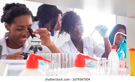 Testing Facility. Young African Female Scientists Or Medical Students, Positive Energetic Women, Work Together Performing Blood, Nucleic Acid And Other Medical Tests On Samples From Covid-19 Patients.