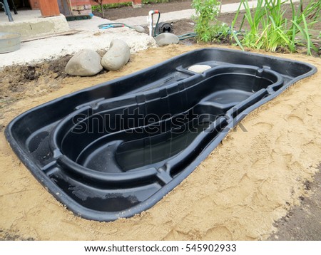 Testing of an installed preformed plastic pond insert filled with some water in the summer garden
