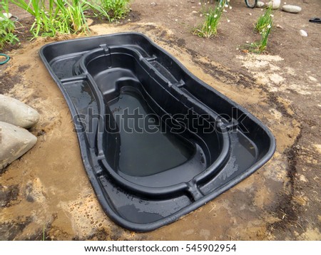 Testing of an installed preformed plastic pond insert filled with some water in the summer garden