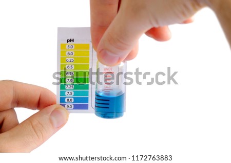 Testing water pH at home. Man determining water pH by comparing the color of liquid in testing vial with attached color scale. Water is alkaline