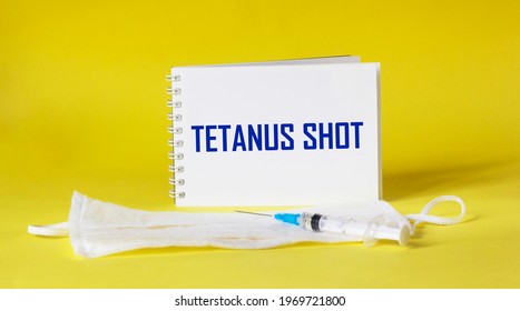 Tetanus Shot Text Is Written On A Notepad And A Yellow Background, Next To A Medical Mask And A Syringe