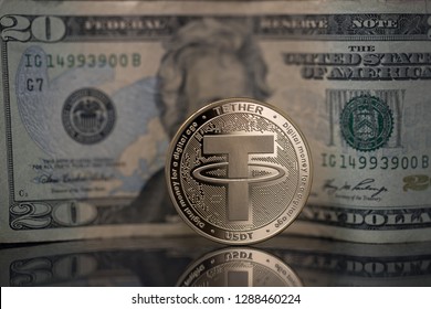 Tether USDT cryptocurrency physical coin placed next to twenty dollars bill on the reflective surface