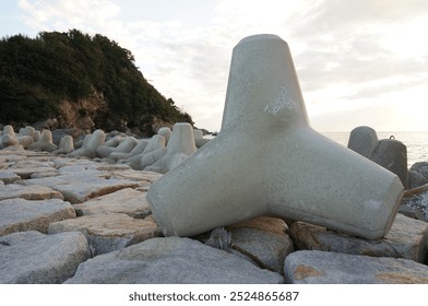 Tetrapods on the breakwater of a small island and a sunset - Powered by Shutterstock