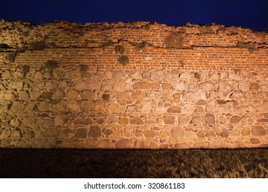 Teutonic Knights Castle Wall Background Illuminated At Night In Torun, Poland, Stone And Brick Medieval Fortification.